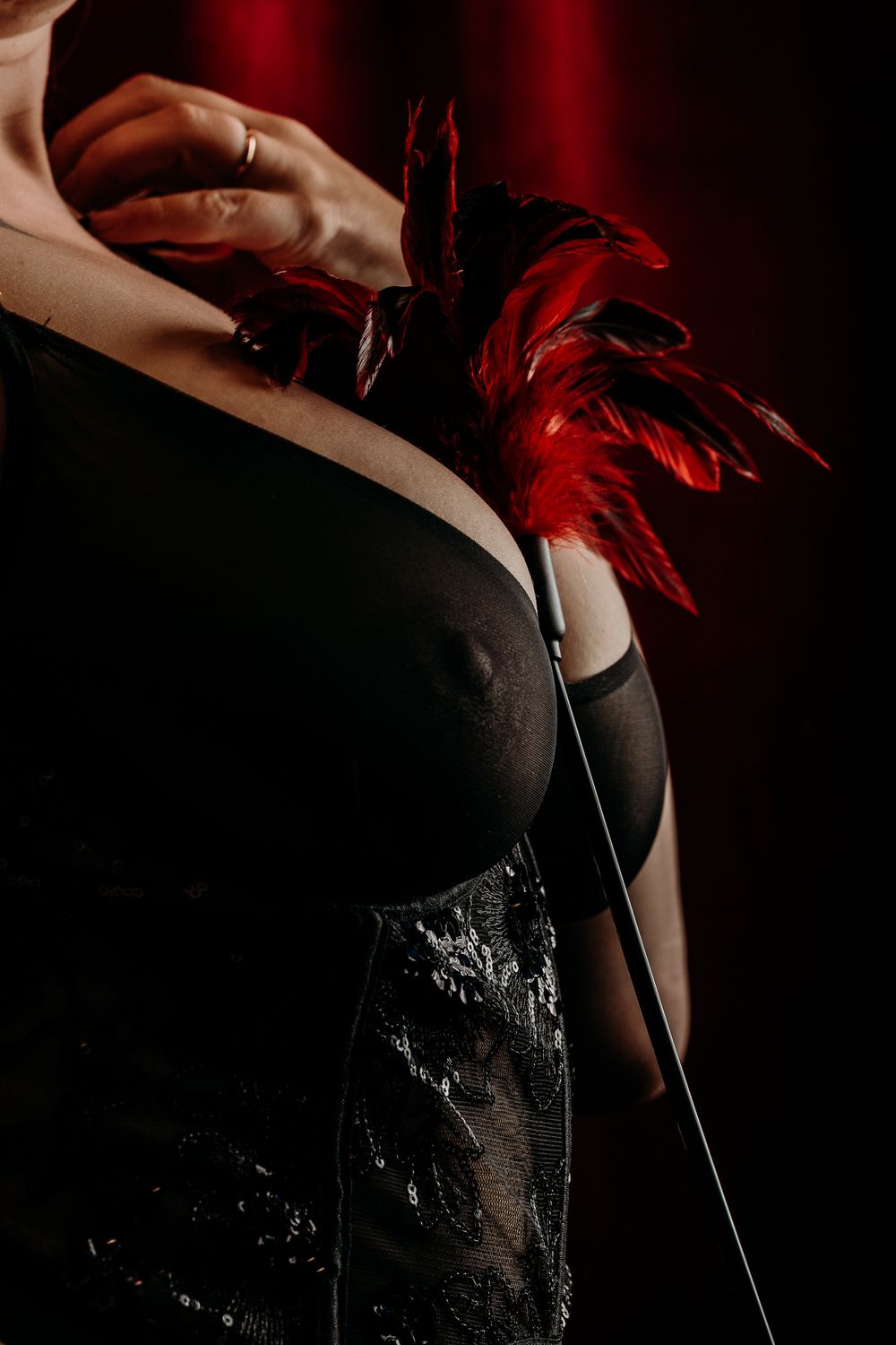 Woman wearing black dress and red accessories in dramatic lighting sequence. West Michigan Boudoir Photographer