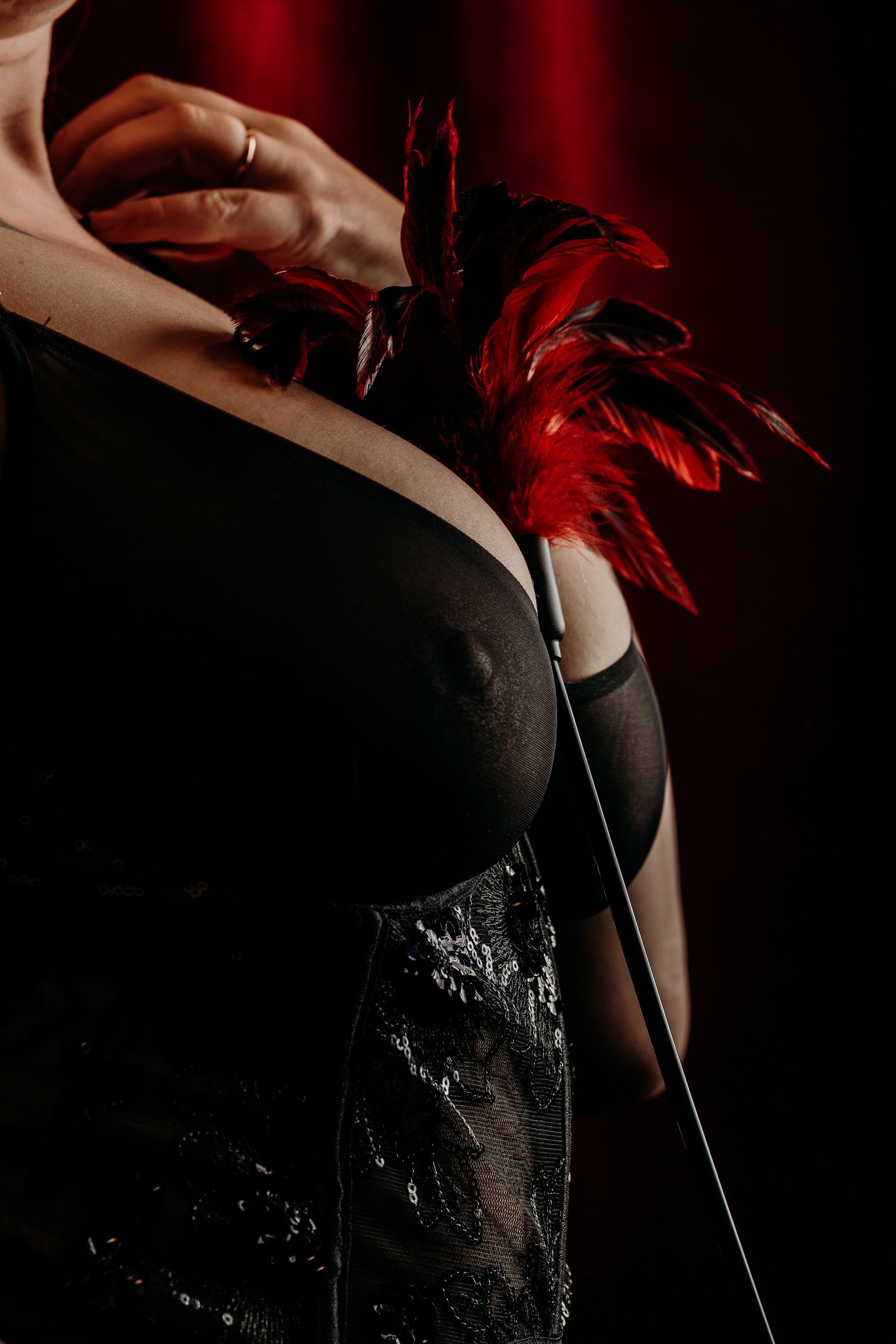 Woman wearing black dress and red accessories in dramatic lighting sequence. West Michigan Boudoir Photographer