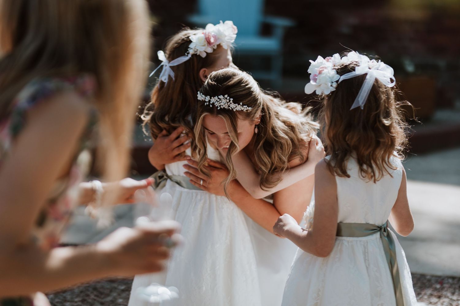 Bride hugs flower girl during wedding drinks reception at Stanford Farm
