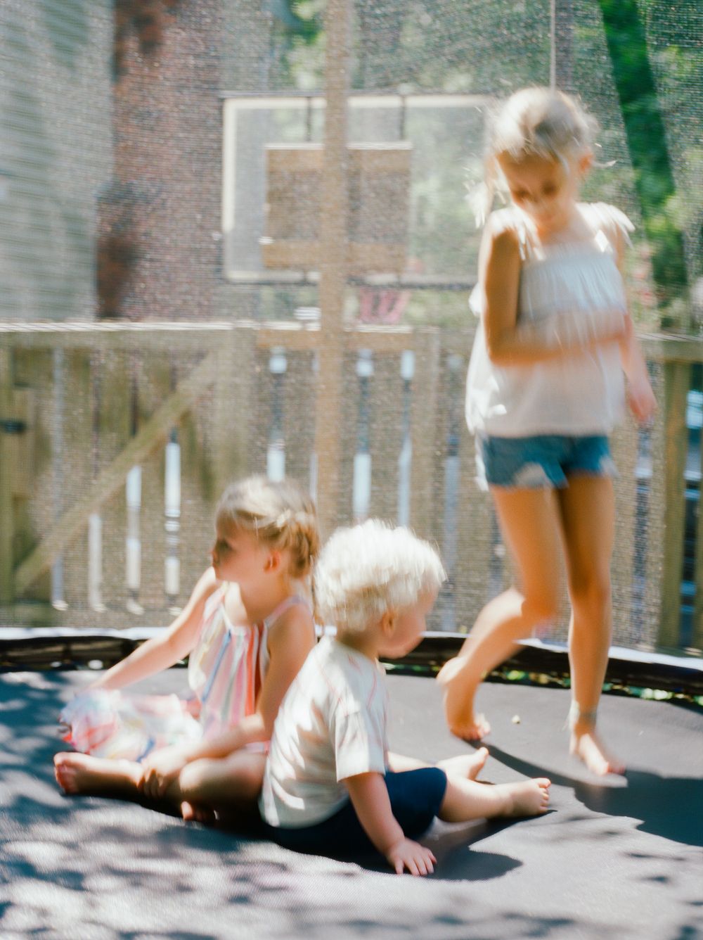 Children playing and bouncing on outdoor trampoline with motion blur effect.