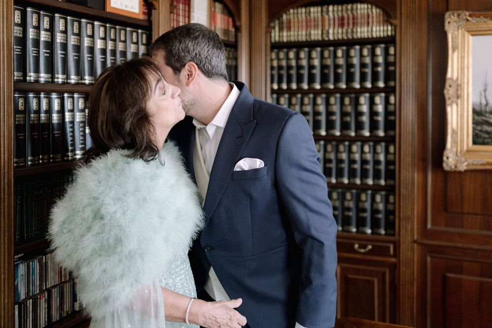 Couple sharing a romantic moment in vintage library with a wall of leather-bound books and wooden shelving.