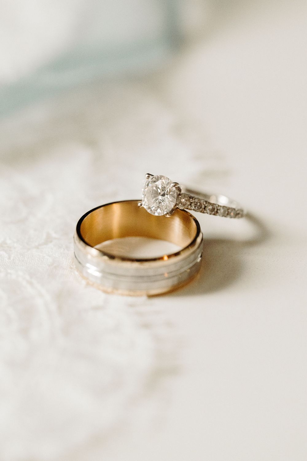 Traditional wedding bands photographed with diamond engagement ring featuring a solitaire stone on soft white surface.
