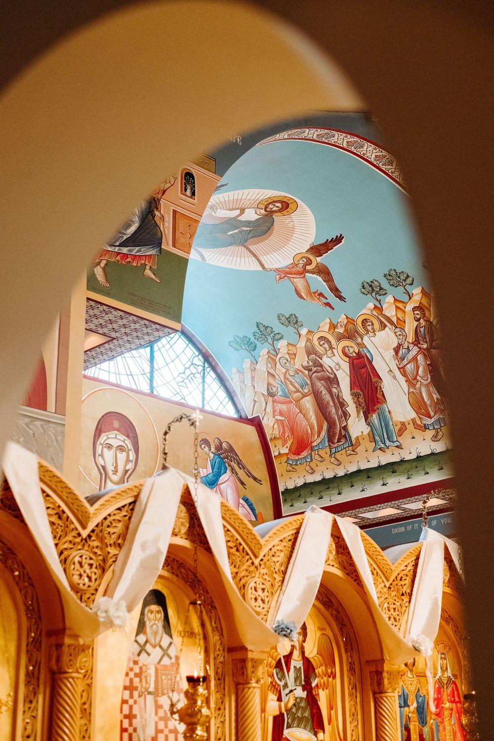 Ornate cathedral ceiling features decorative religious murals and gilded arches in warm golden tones.