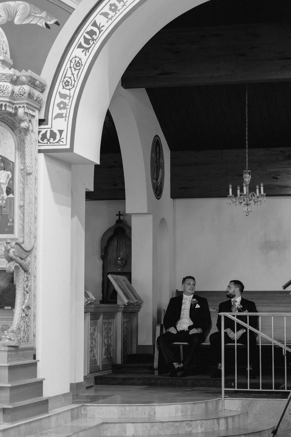 An elegant church interior with white arches and ornate architectural details creates a dramatic monochrome scene.