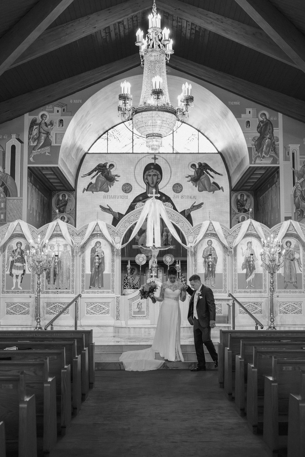 Black and white photo of a church interior with decorative wall murals and chandelier lighting.