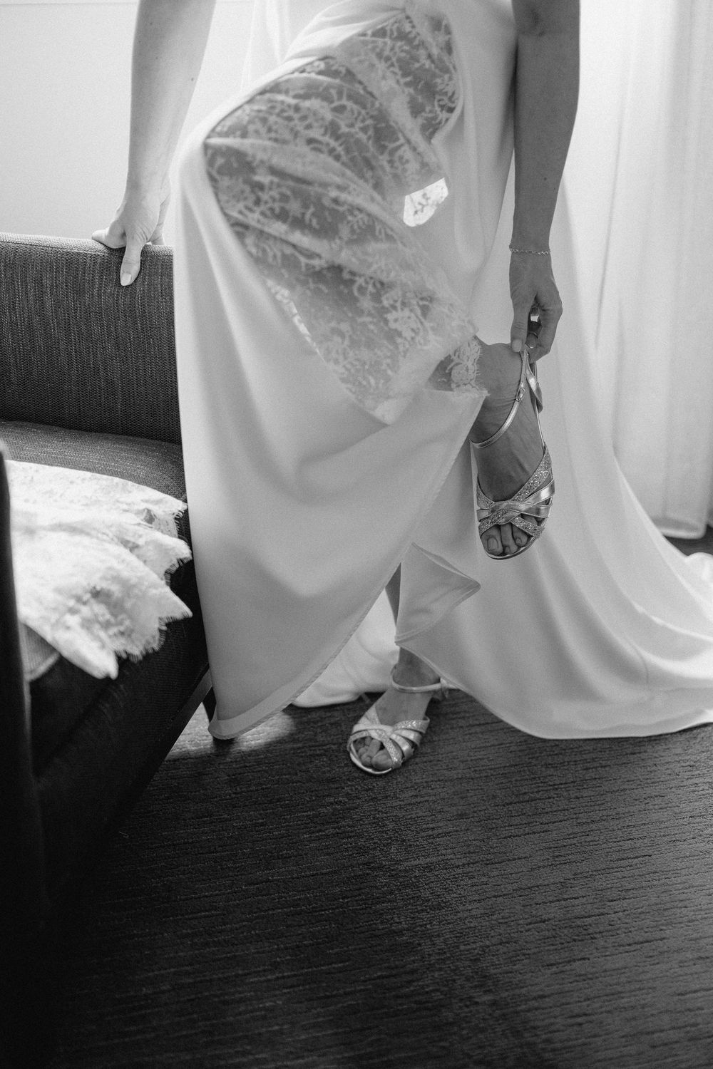 A black and white photo series showing closeup details of a wedding dress and shoes on dark hardwood flooring.
