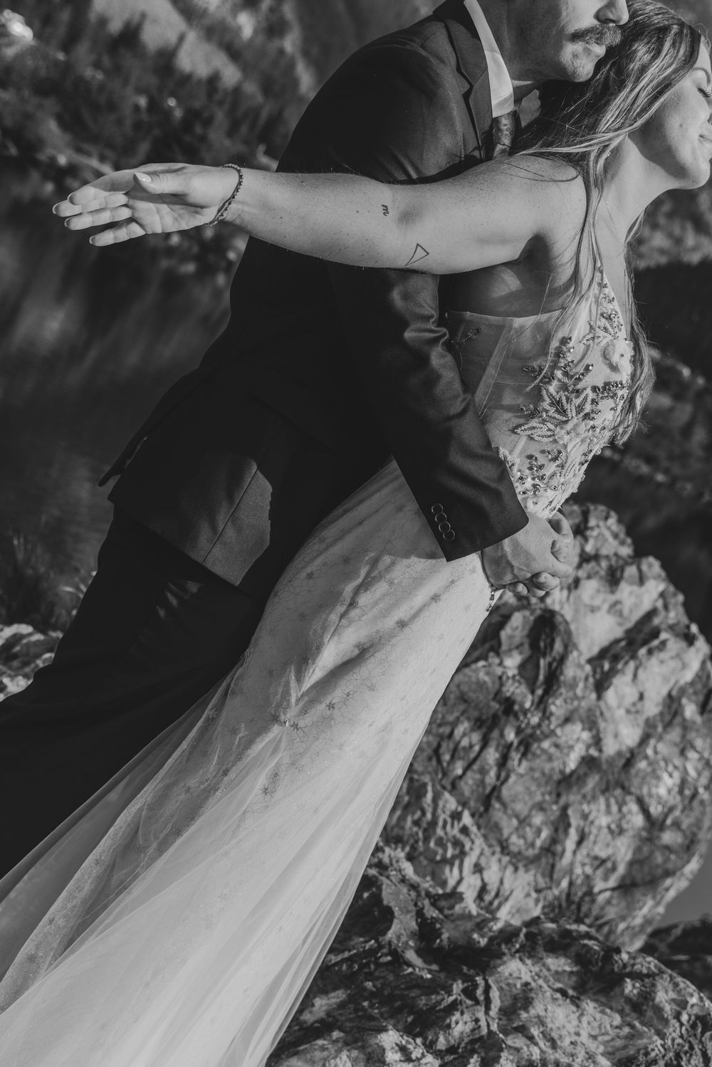 A graceful figure in a white dress spins across a scenic outdoor setting with dramatic mountain rocks in the background.