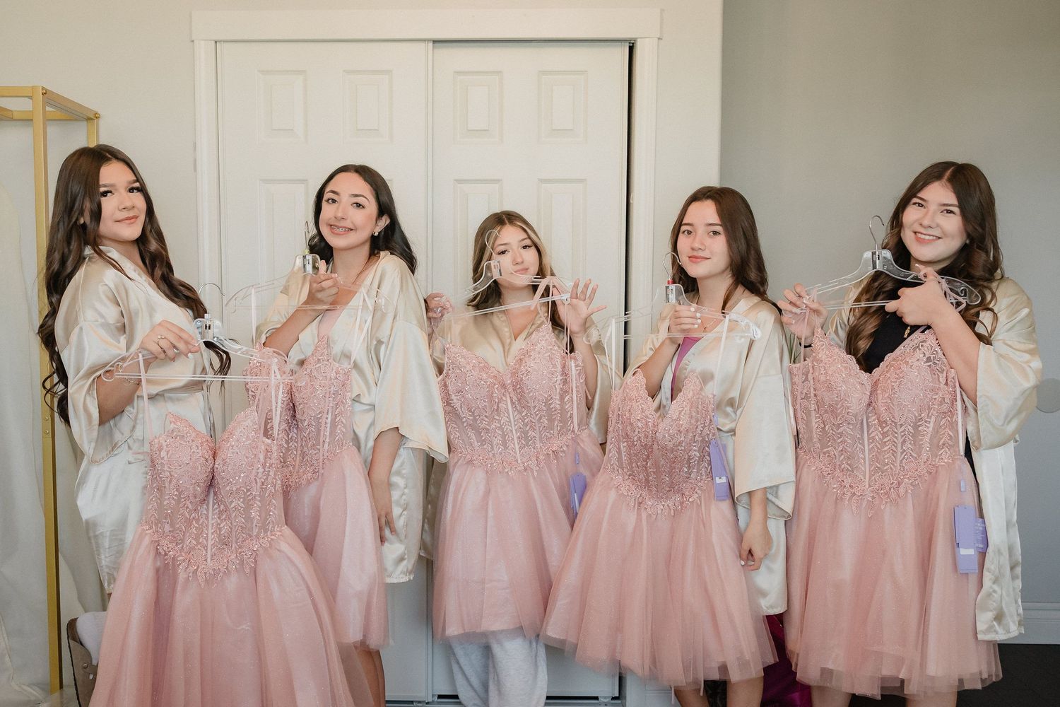 A group wearing matching pink robes poses together in a bright indoor setting.