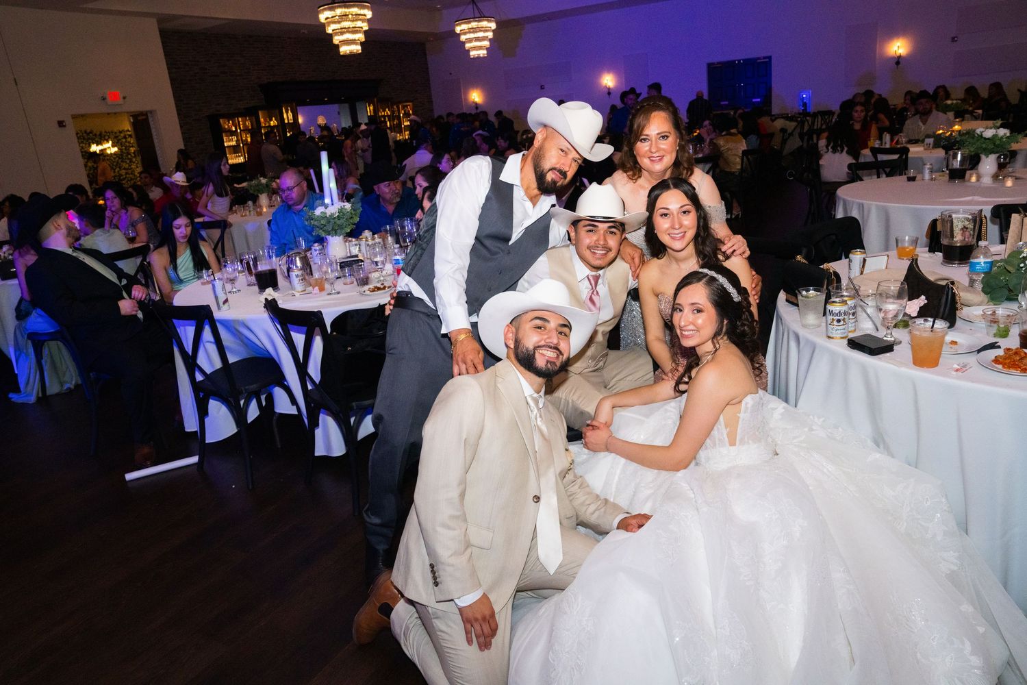 Wedding reception dance floor with guests celebrating in formal attire and cowboy hats.