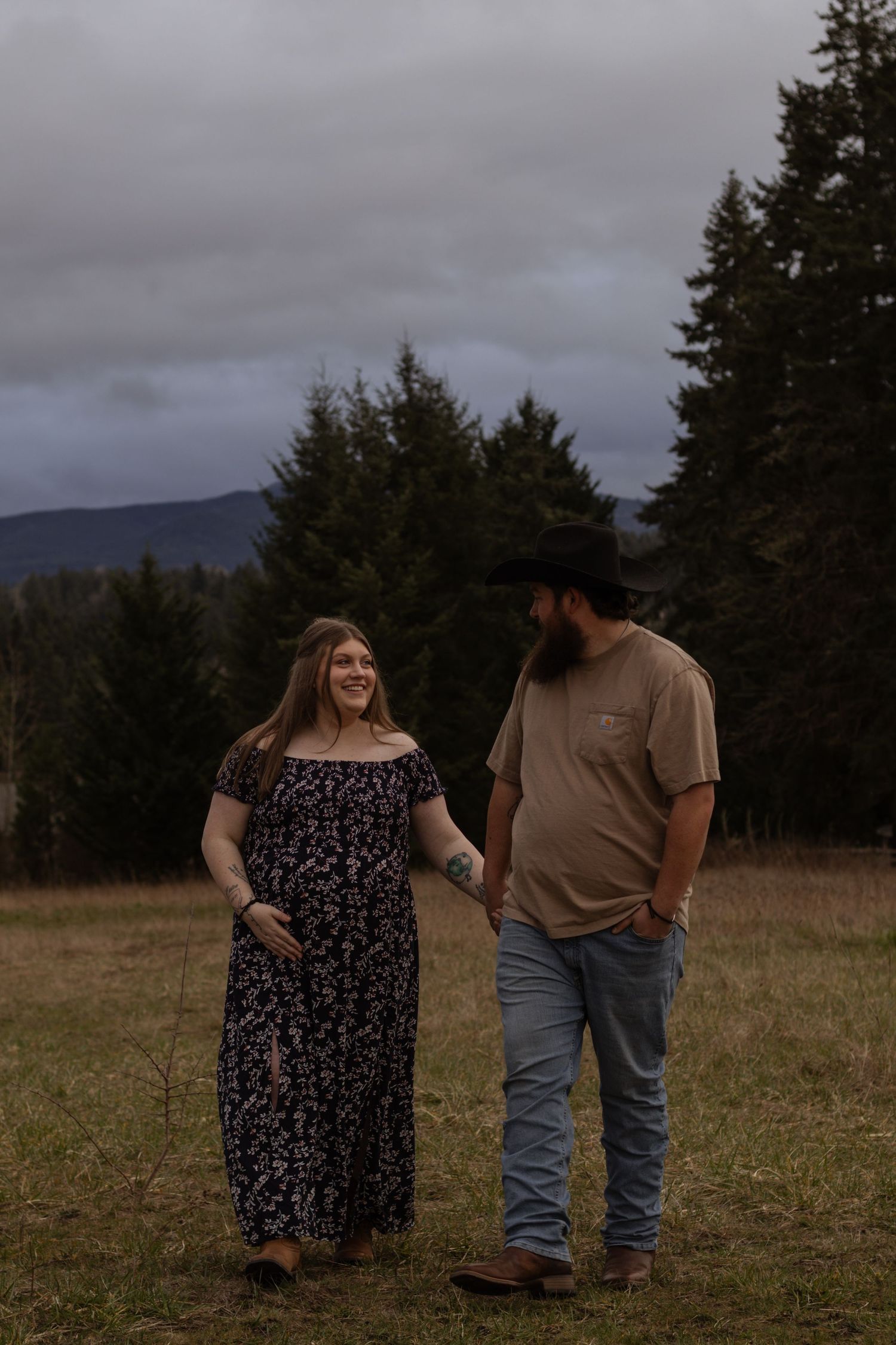 pregnant Couple walking and laughing in eatonville washington field captured by pierce county photographer