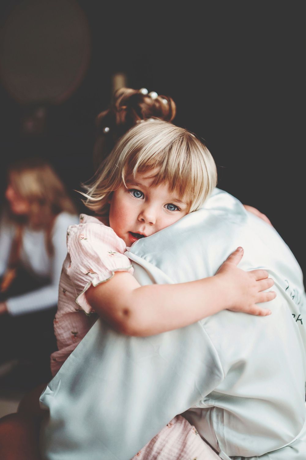 Young child in a dark room hugging a large white pillow with emotion.