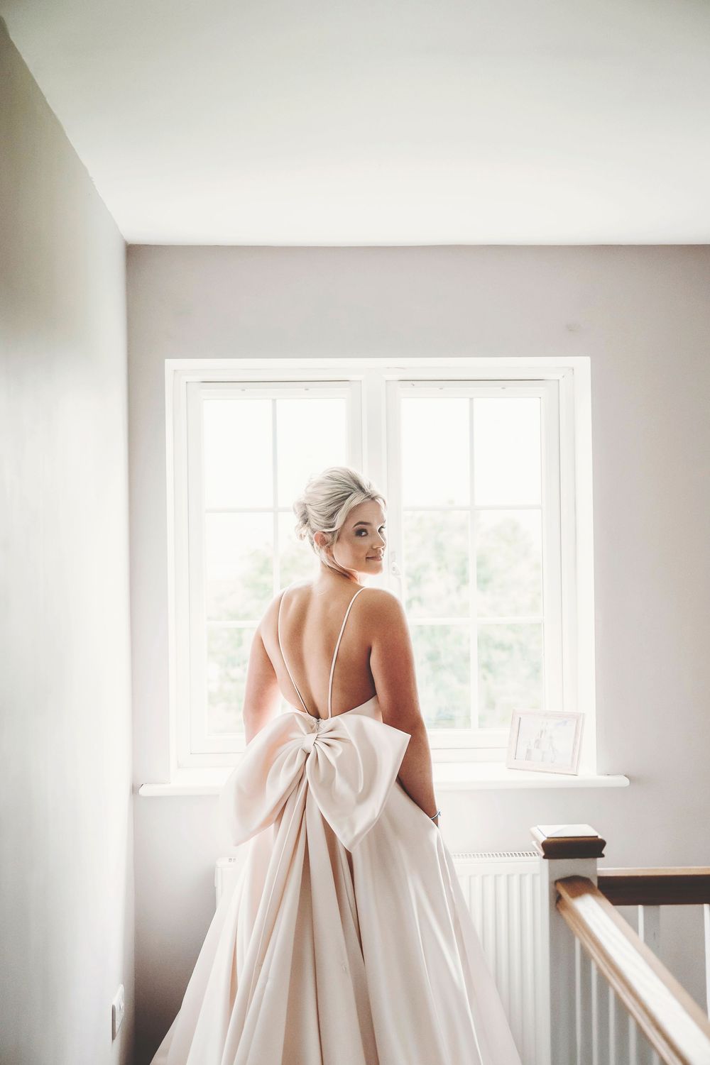 Back view of a wedding dress with an elegant oversized bow detail in a bright white room.