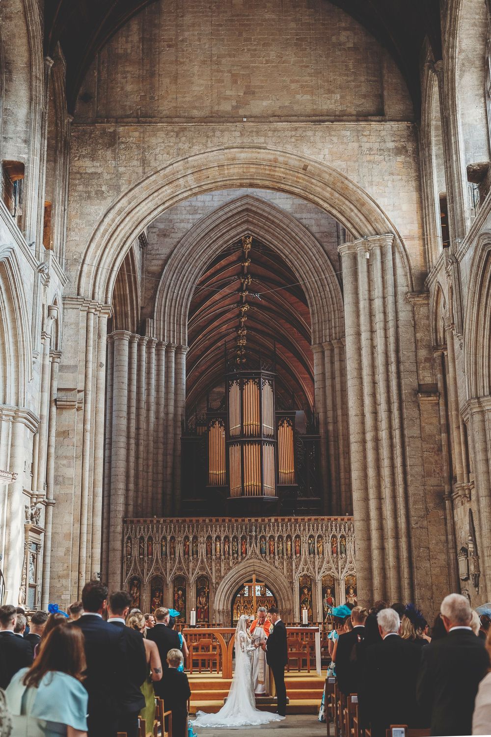 A panoramic view of a grand cathedral interior with gothic arches and gathered congregation during a ceremony.