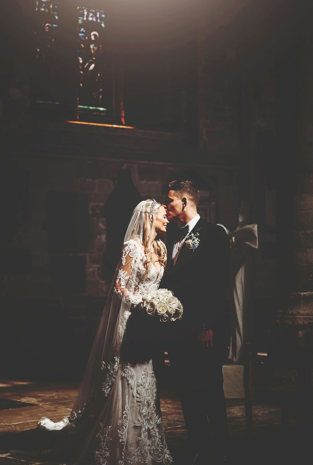 A couple sharing a romantic dance together on their wedding day in a dimly lit venue.