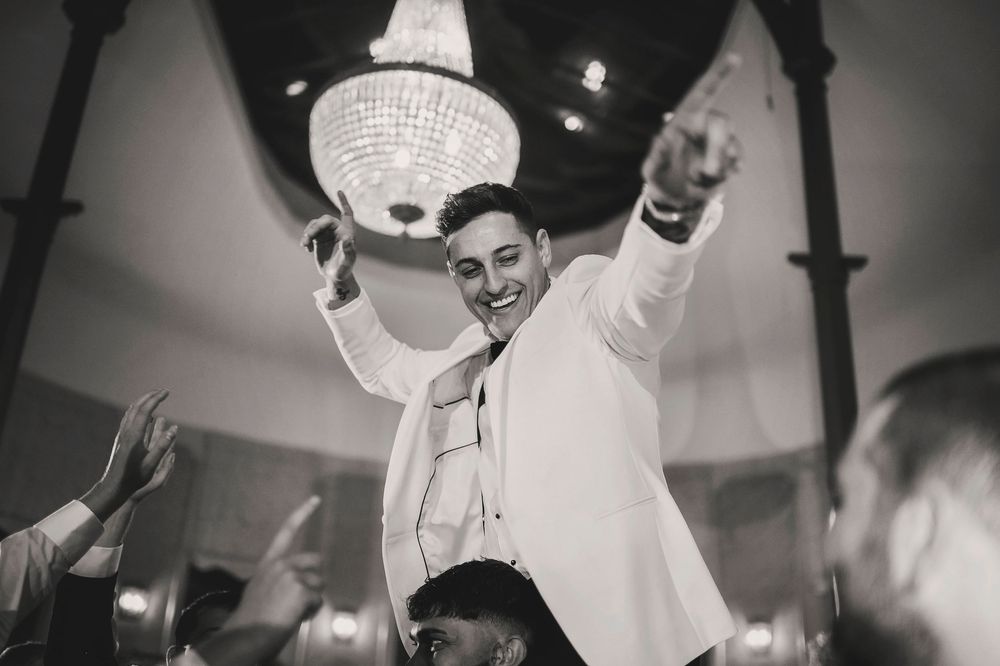 Wedding reception dance floor crowd celebrating under disco balls and lights.