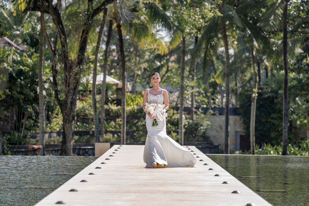 Couple enjoys romantic moments at a tropical poolside resort surrounded by lush palm trees and sunshine at Conrad Bali Resort.