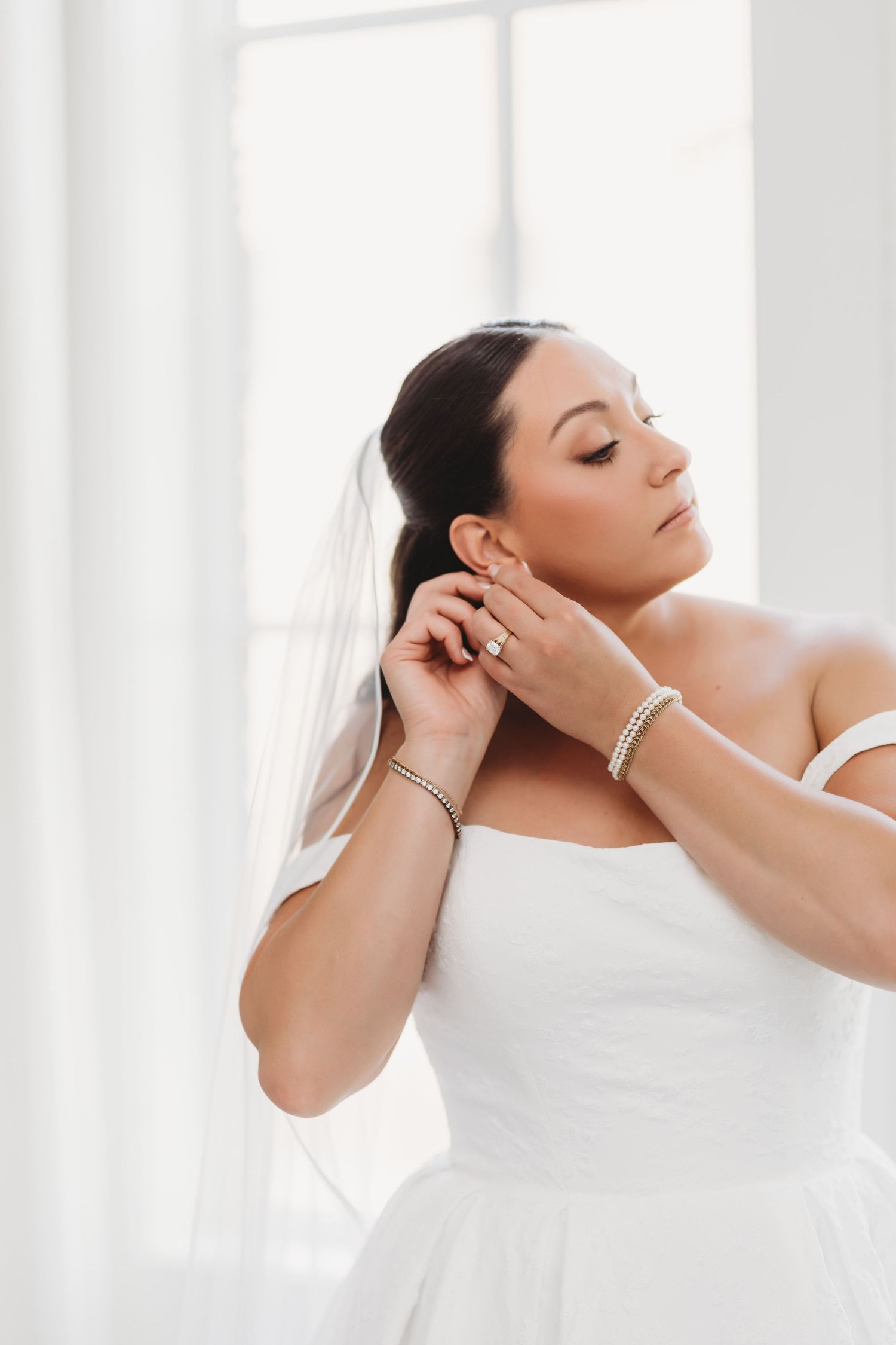 Woman with dark hair lounging in white against light background in serene spa-like setting.