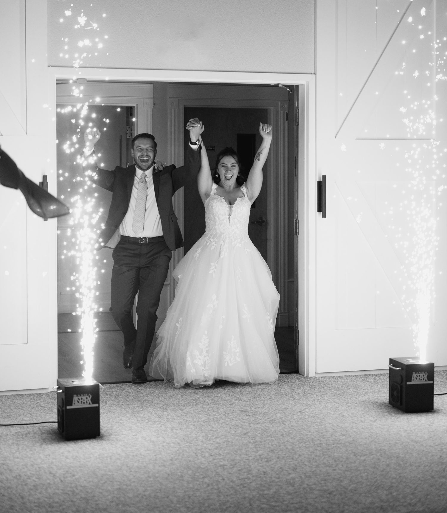 A wedding couple makes a dramatic entrance through doorways surrounded by sparklers creating a magical atmosphere.
