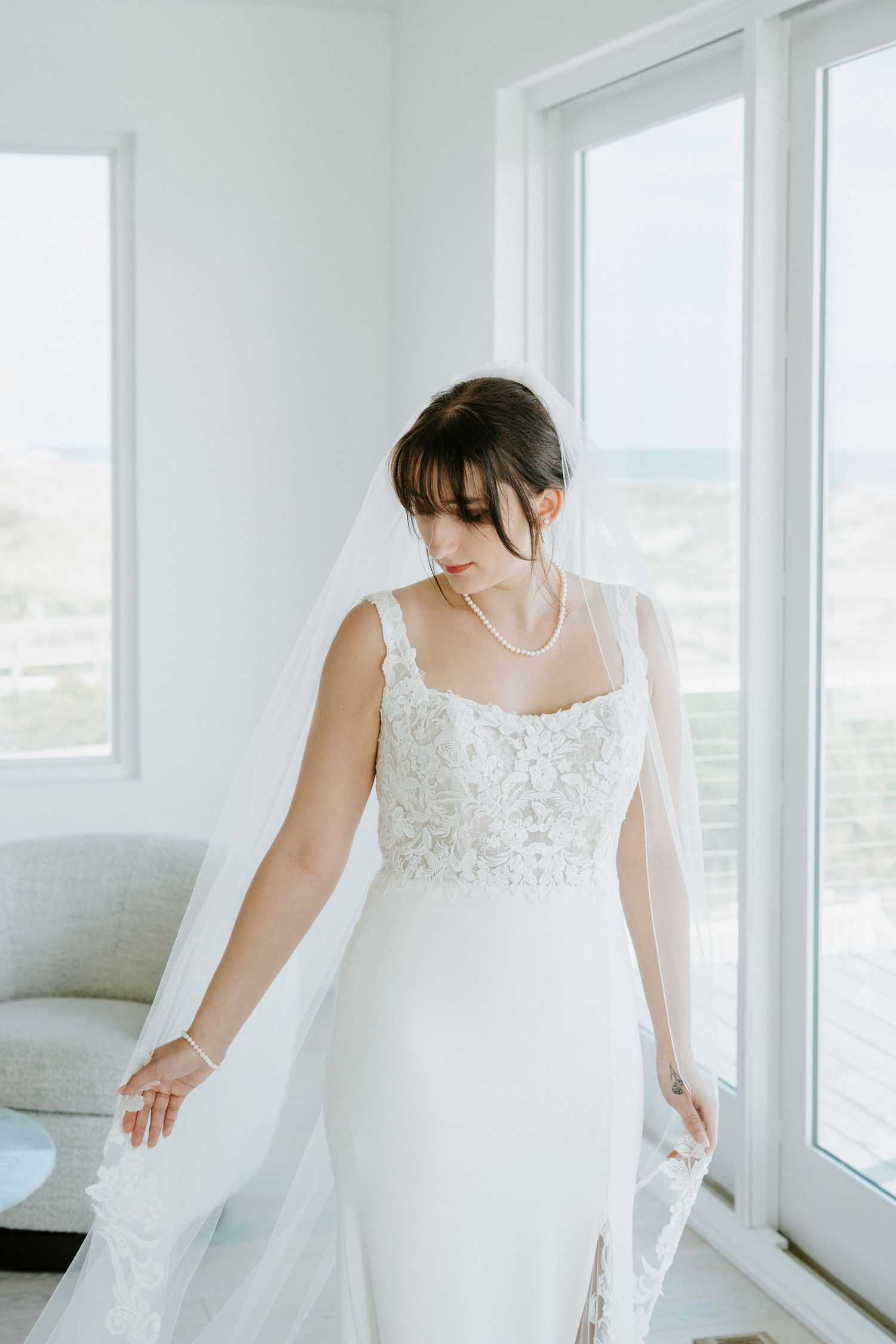 Bride in traditional white wedding gown twirls gracefully by bright window in luminous natural light.