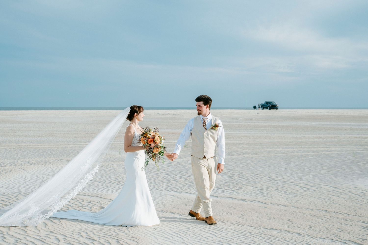 A romantic beach wedding photo series showing a couple walking and posing on pristine white sand with flowing fabric.