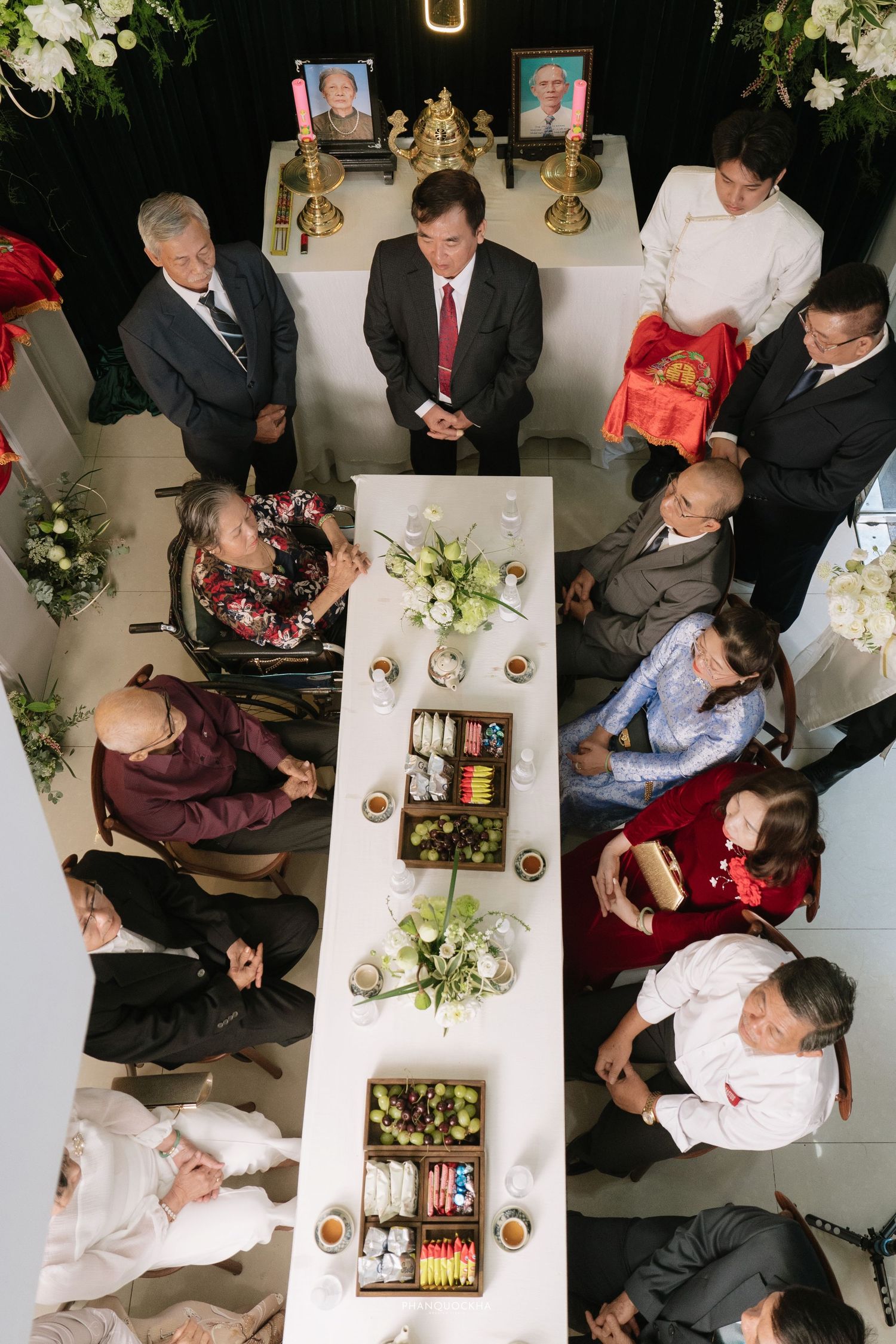 Overhead view of traditional Vietnamese wedding ceremony with family gathered around ceremonial table with offerings.
