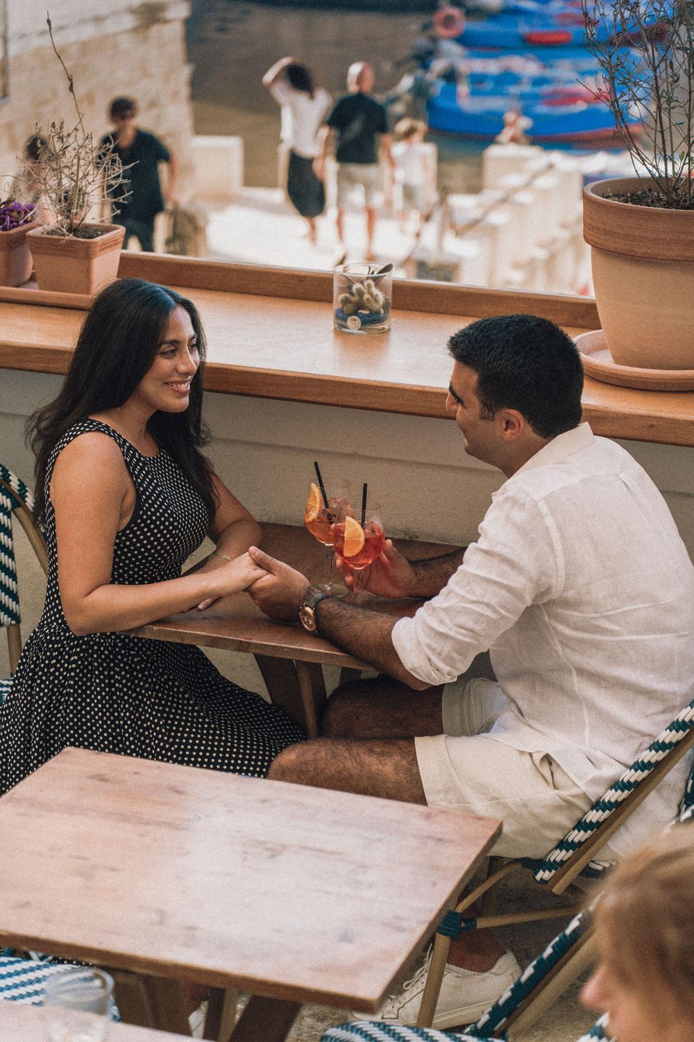 A couple sits together at a casual restaurant with polka dot decor, sharing a meal at a wooden table.