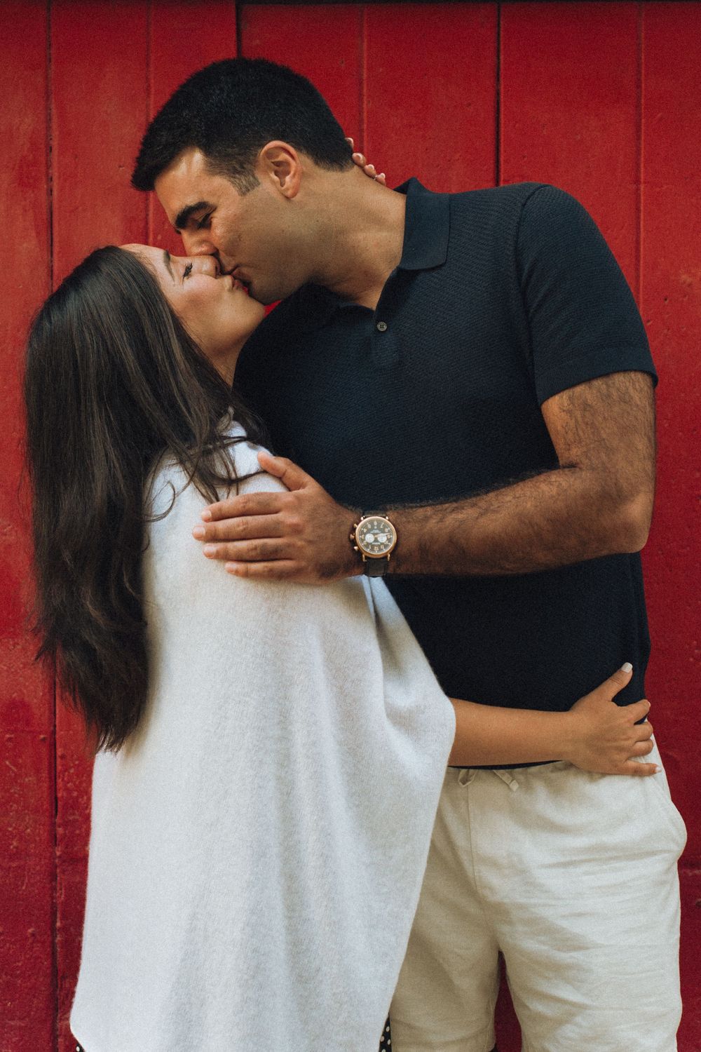 Sequence of romantic photos showing a couple in white and black clothing embracing against a red backdrop.