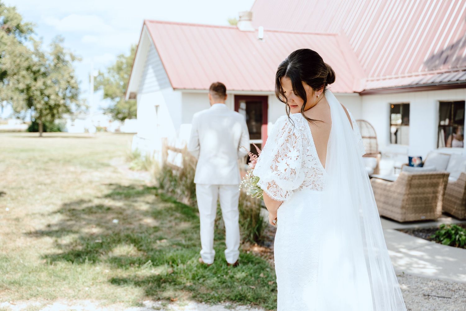 Couple in white and tan embrace in a romantic series of wedding photos in a sunlit field.