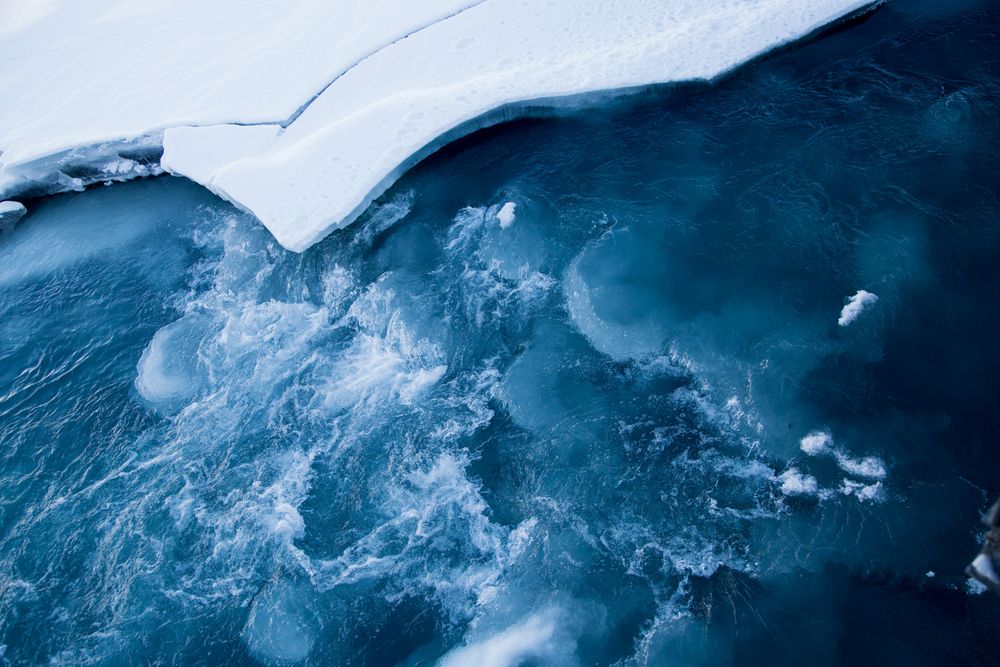 Aerial view of turquoise glacial ice and water forming mesmerizing patterns in a frozen landscape.