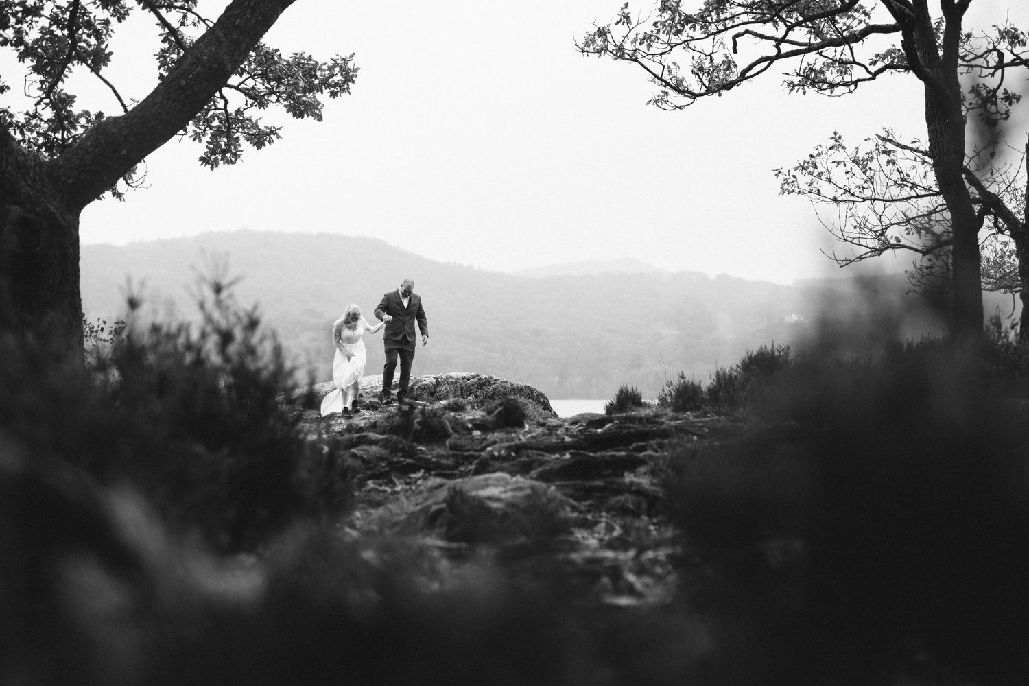 A couple runs playfully through an outdoor field during a romantic photoshoot session.
