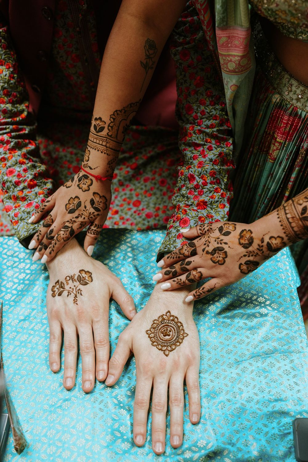 Time-lapse sequence showing traditional henna design being applied on hands against a blue background.