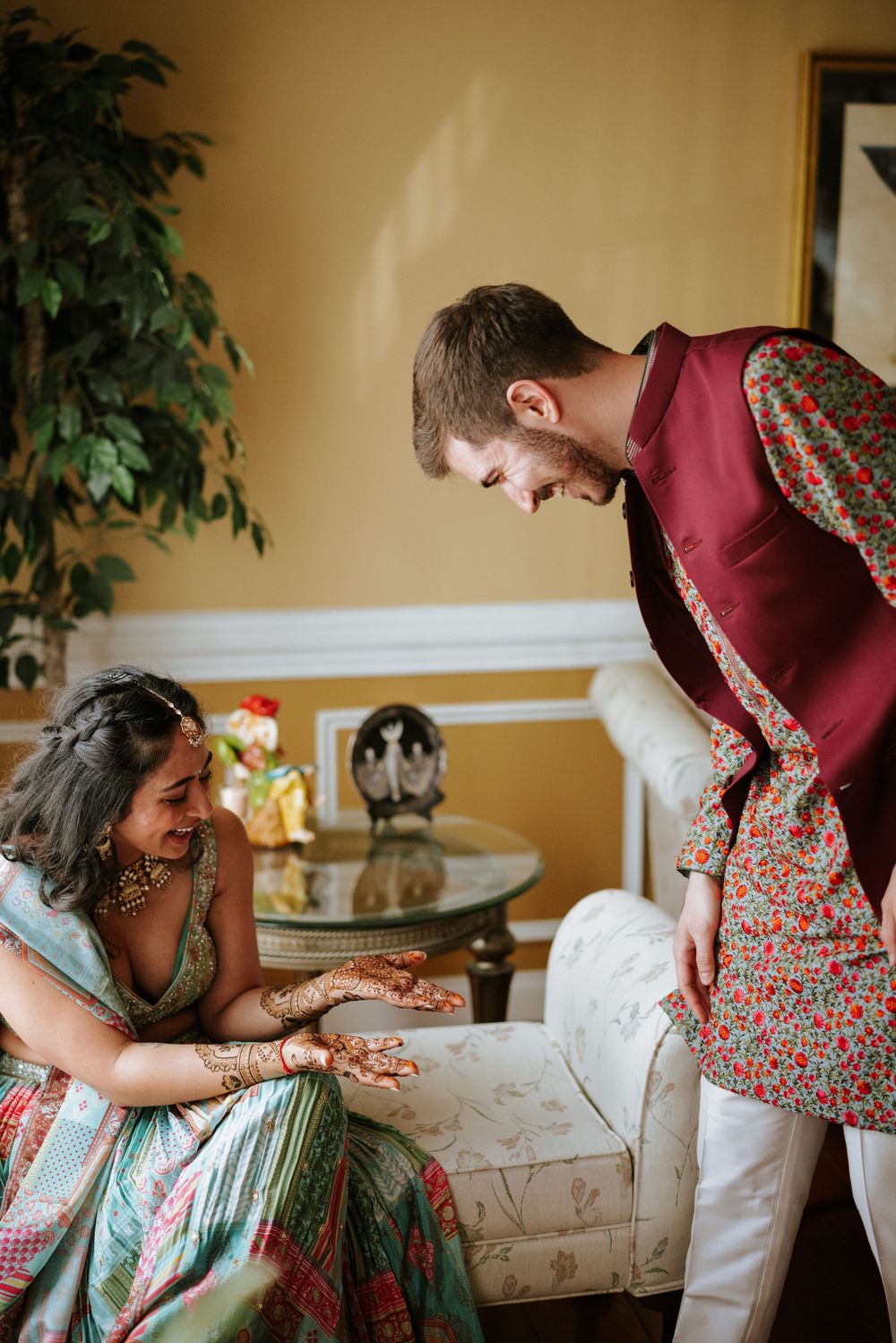 Two people in colorful traditional Indian attire share a moment in an elegantly decorated room.