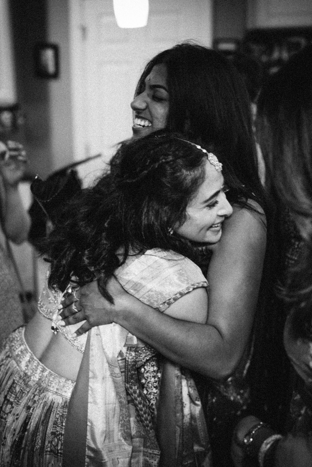 Joyful wedding celebration moments captured in black and white showing friends embracing and laughing together.
