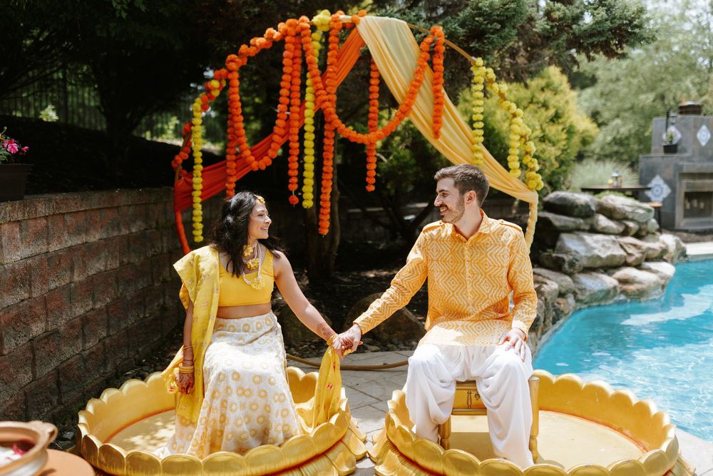 Vibrant orange and yellow marigold decorations adorn an outdoor Indian wedding celebration setting.