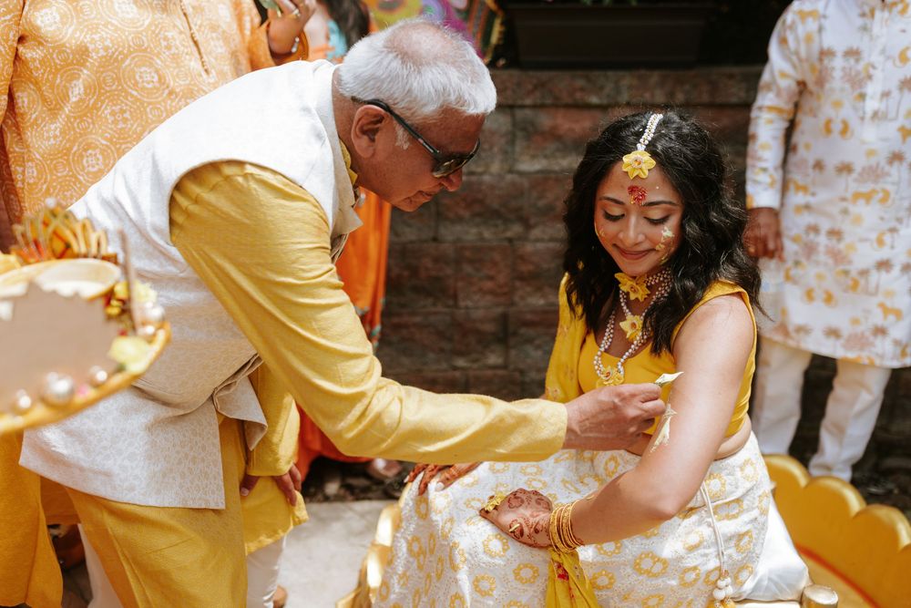 A traditional Indian Haldi ceremony shows yellow turmeric powder being applied during a pre-wedding ritual.