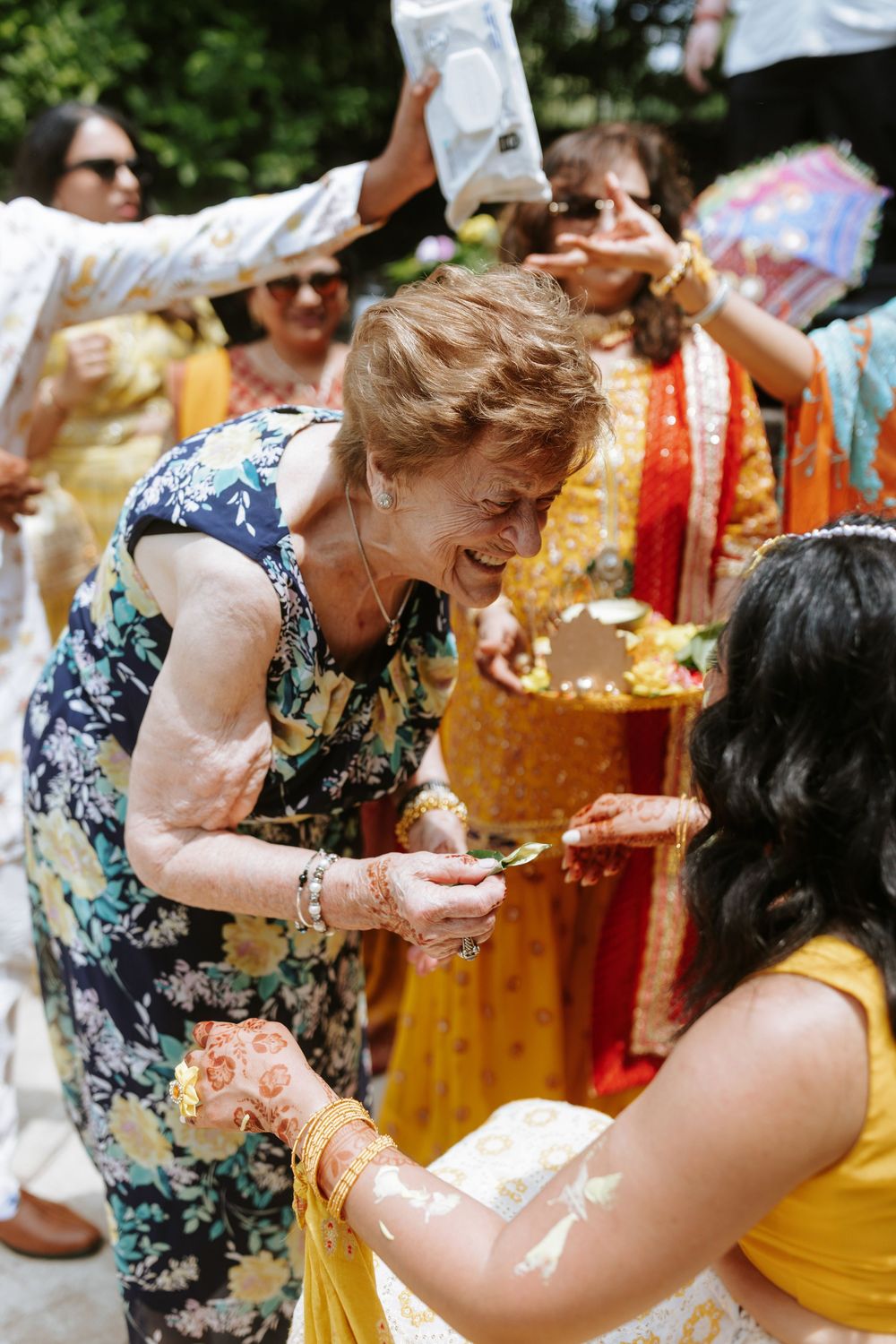 Guests celebrate at an outdoor wedding ceremony with colorful traditional Indian attire and festive decorations.