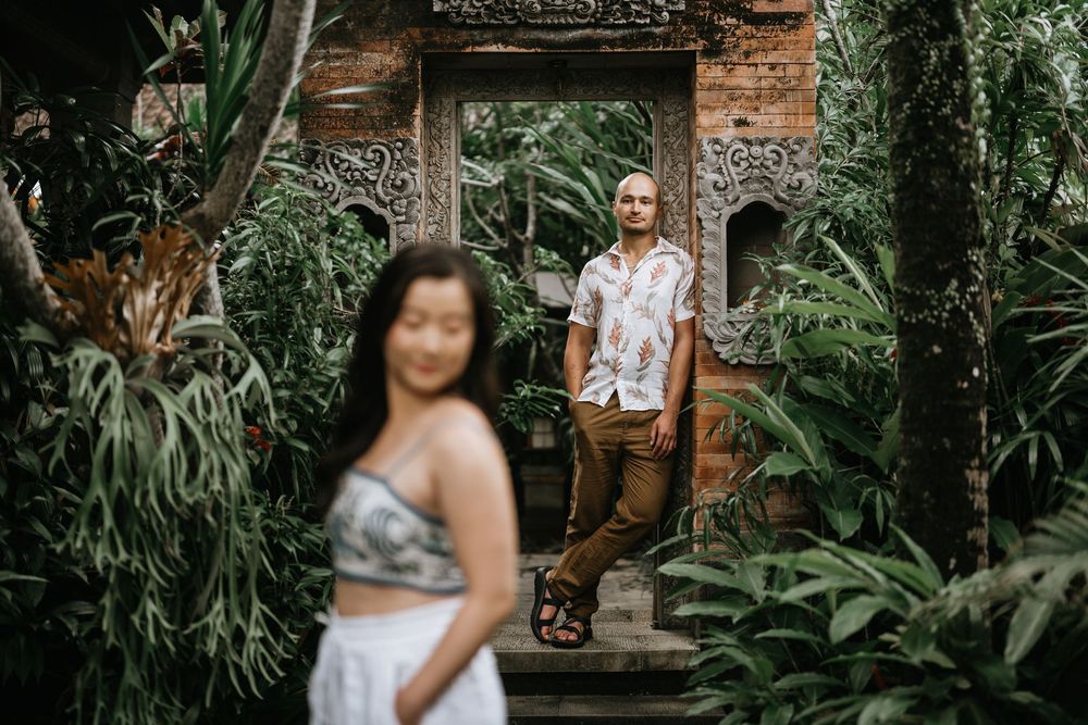 Artistic portrait at traditional Balinese stone gateway surrounded by tropical greenery.