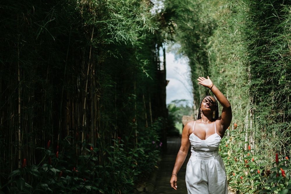 Person in white dress walking through bamboo forest path.
