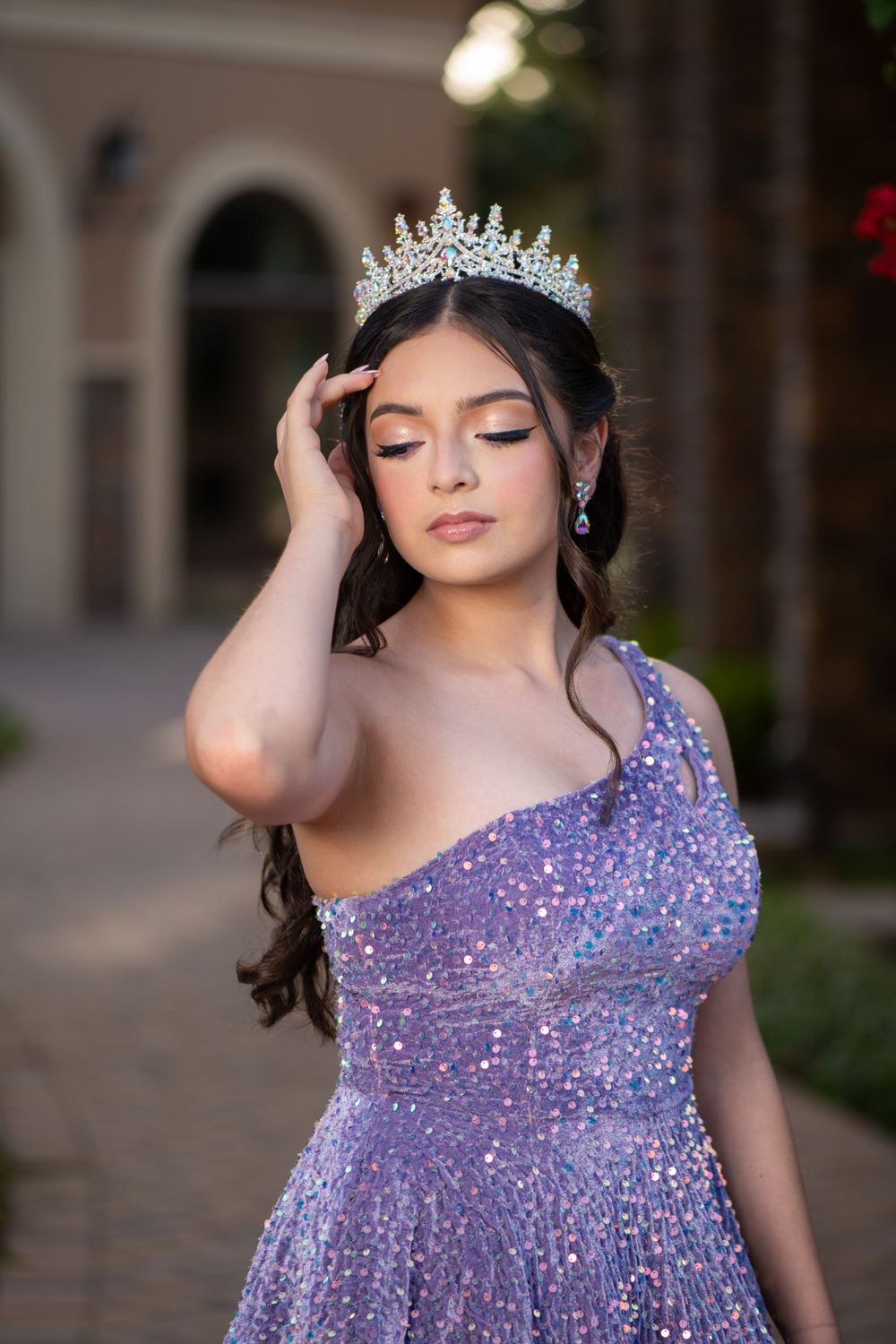 Sparkling purple gown with tiara and jewelry photographed in an elegant outdoor setting.