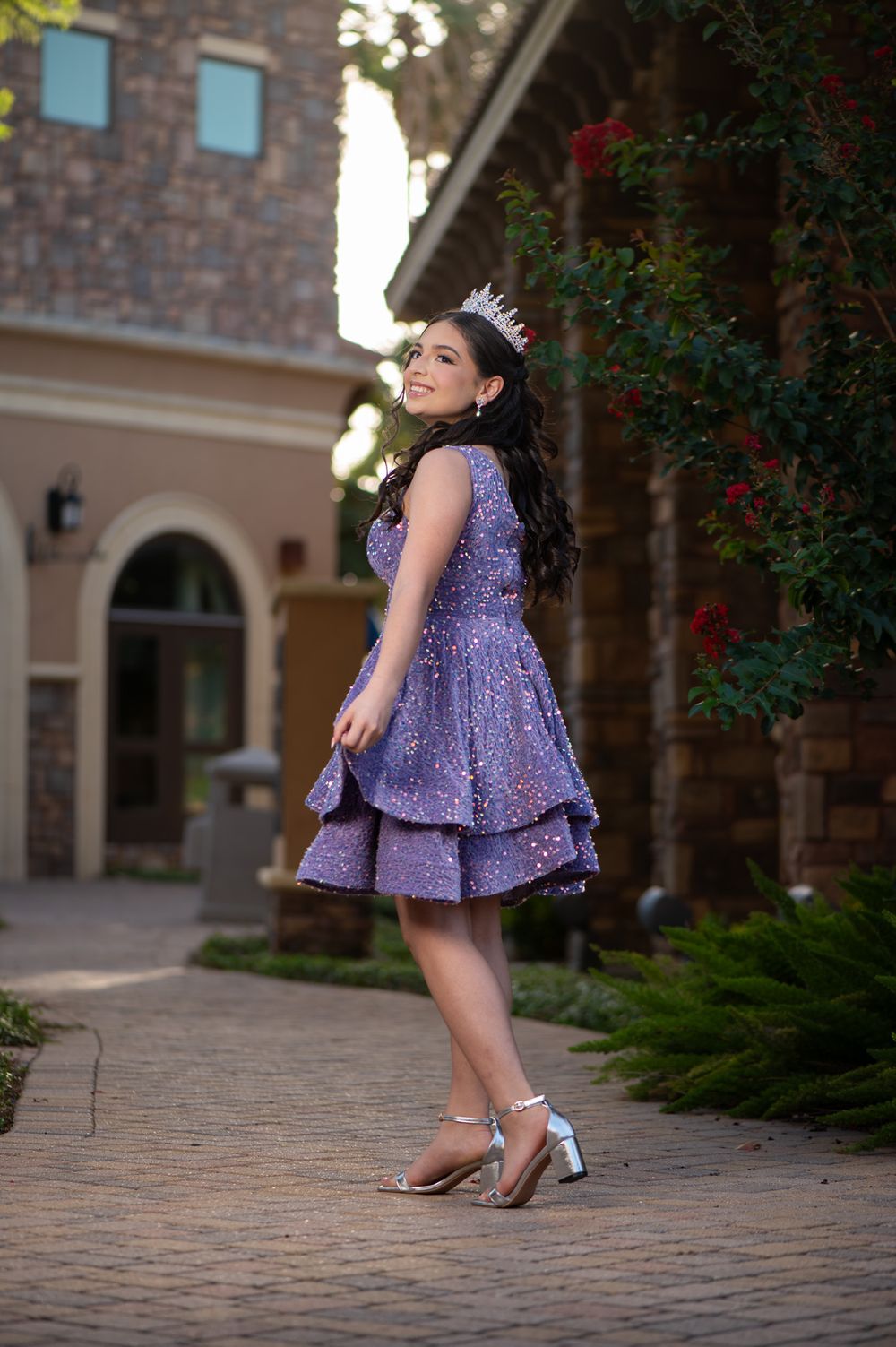 Short purple sparkly dress with tiara shown in a twirling pose on brick walkway.