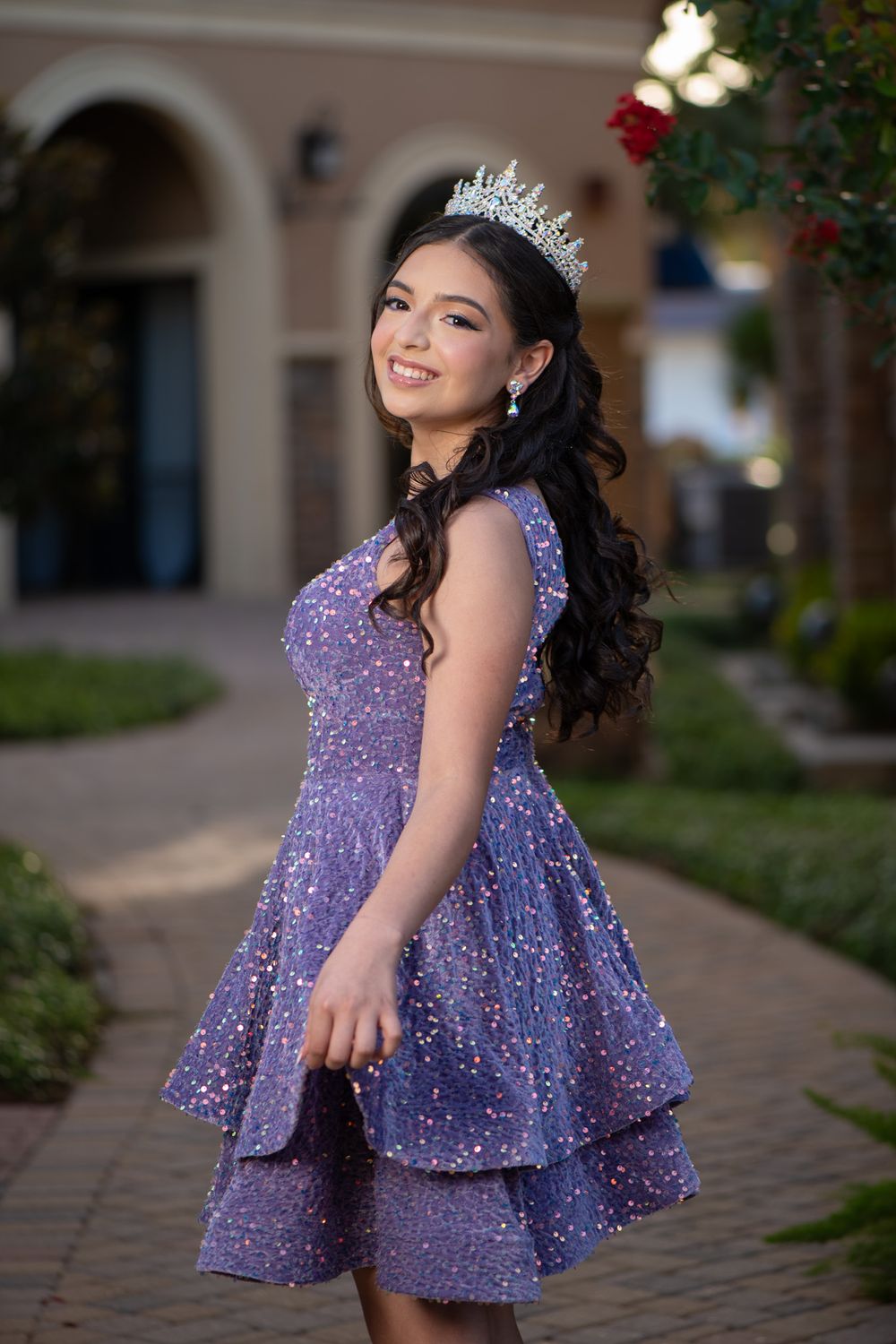 Sparkling purple cocktail dress and crystal tiara captured in front of Mediterranean-style architecture.