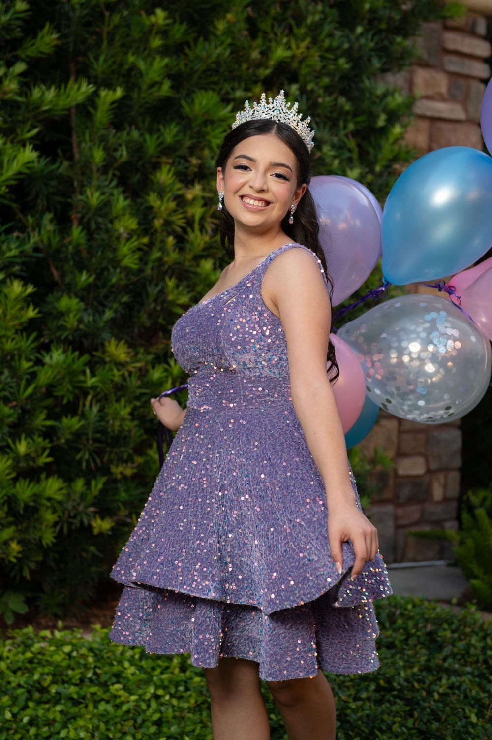 A festive purple sequined dress shimmers in the sunlight alongside colorful party balloons.