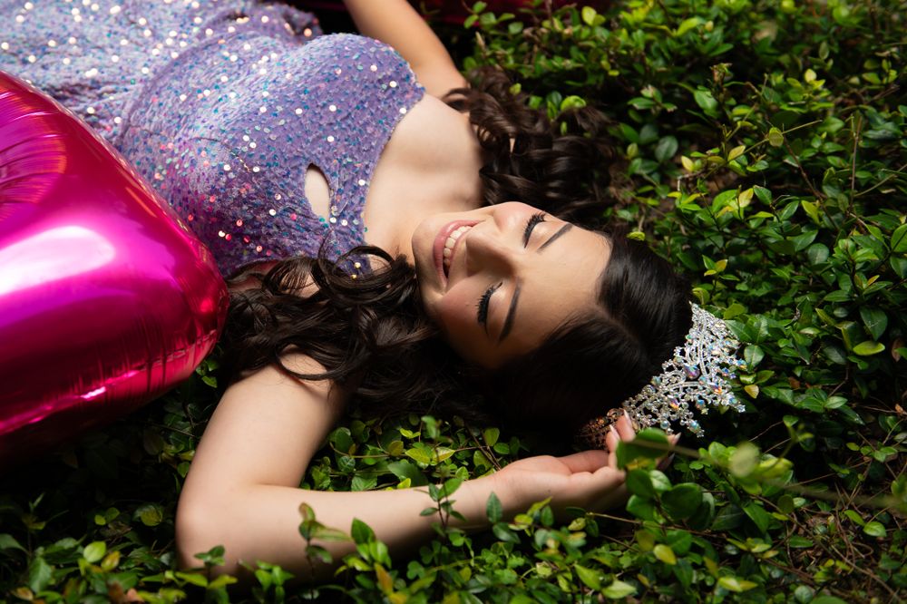 Dreamy portrait with sparkly dress and pink balloon decorations against garden foliage.