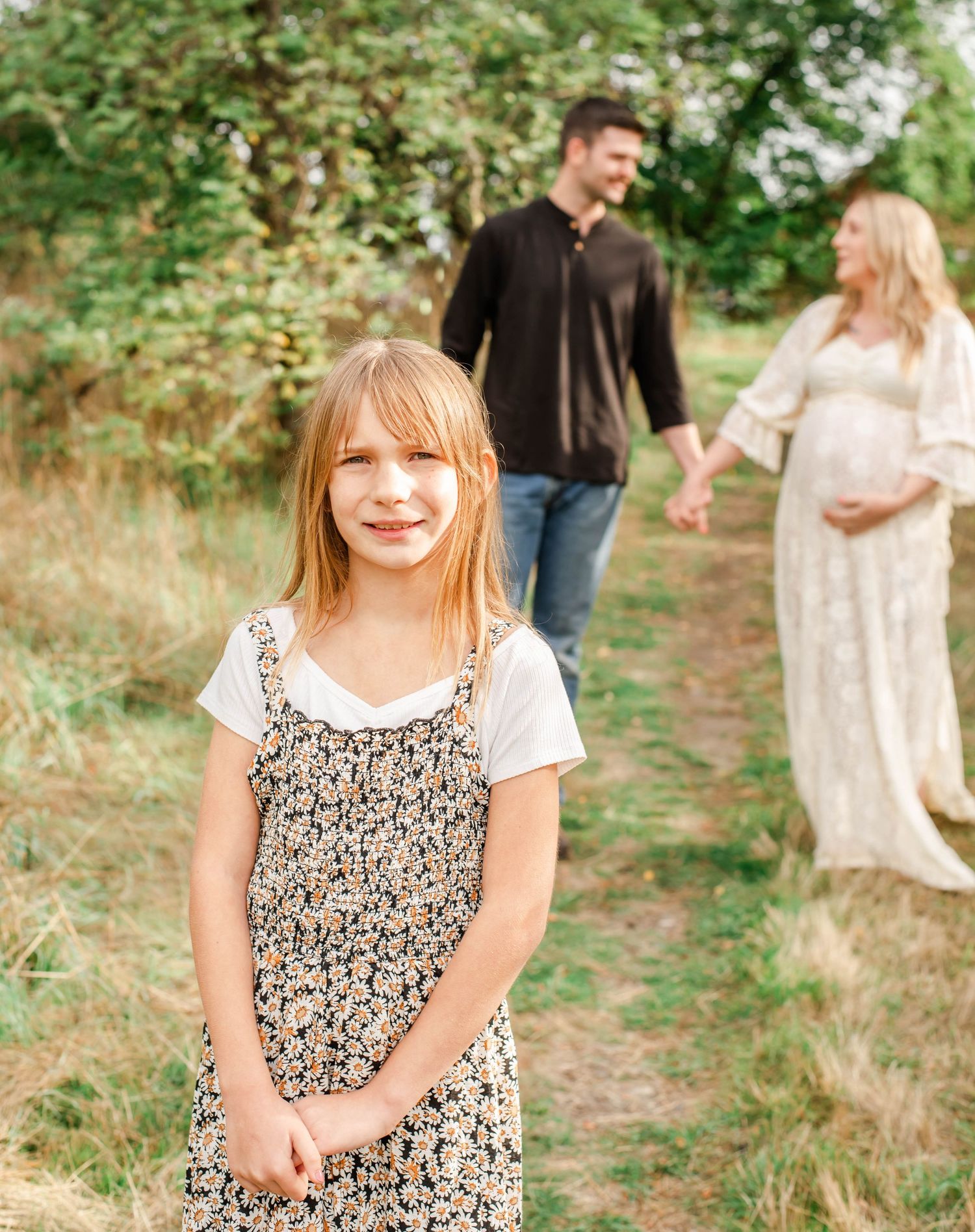 A family walks together on a wooded path during a sunny outdoor photo session in nature.