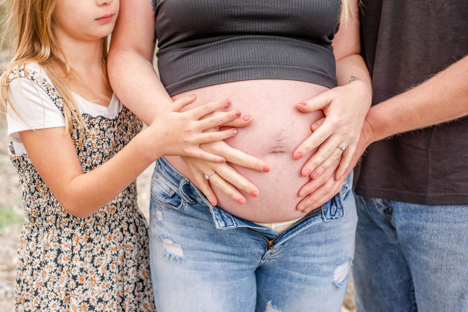 A maternity photo series shows a close-up of a pregnant belly with small hands touching it in different frames.