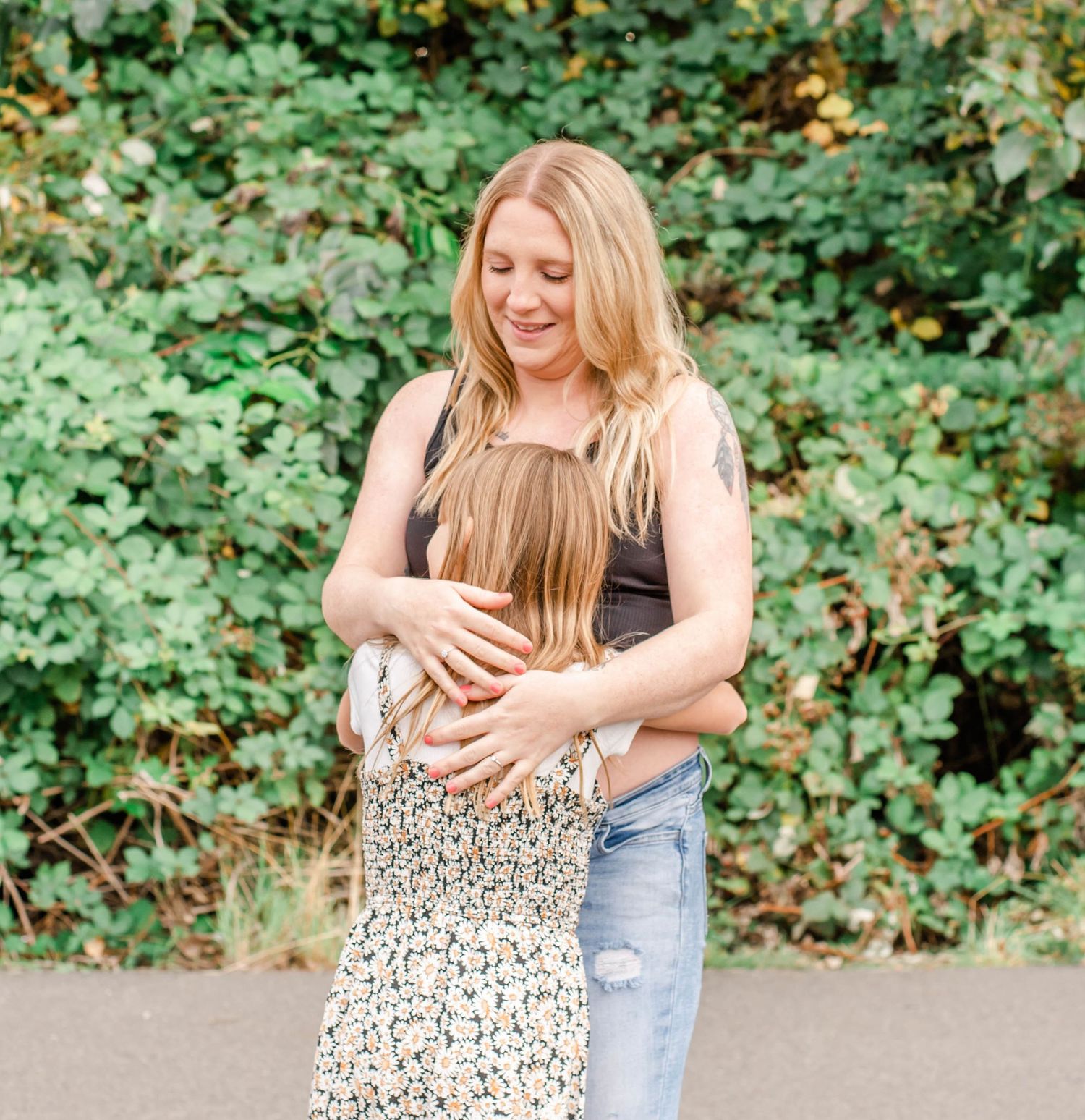 A tender moment captured in nature as two people share a loving embrace amidst lush green foliage.
