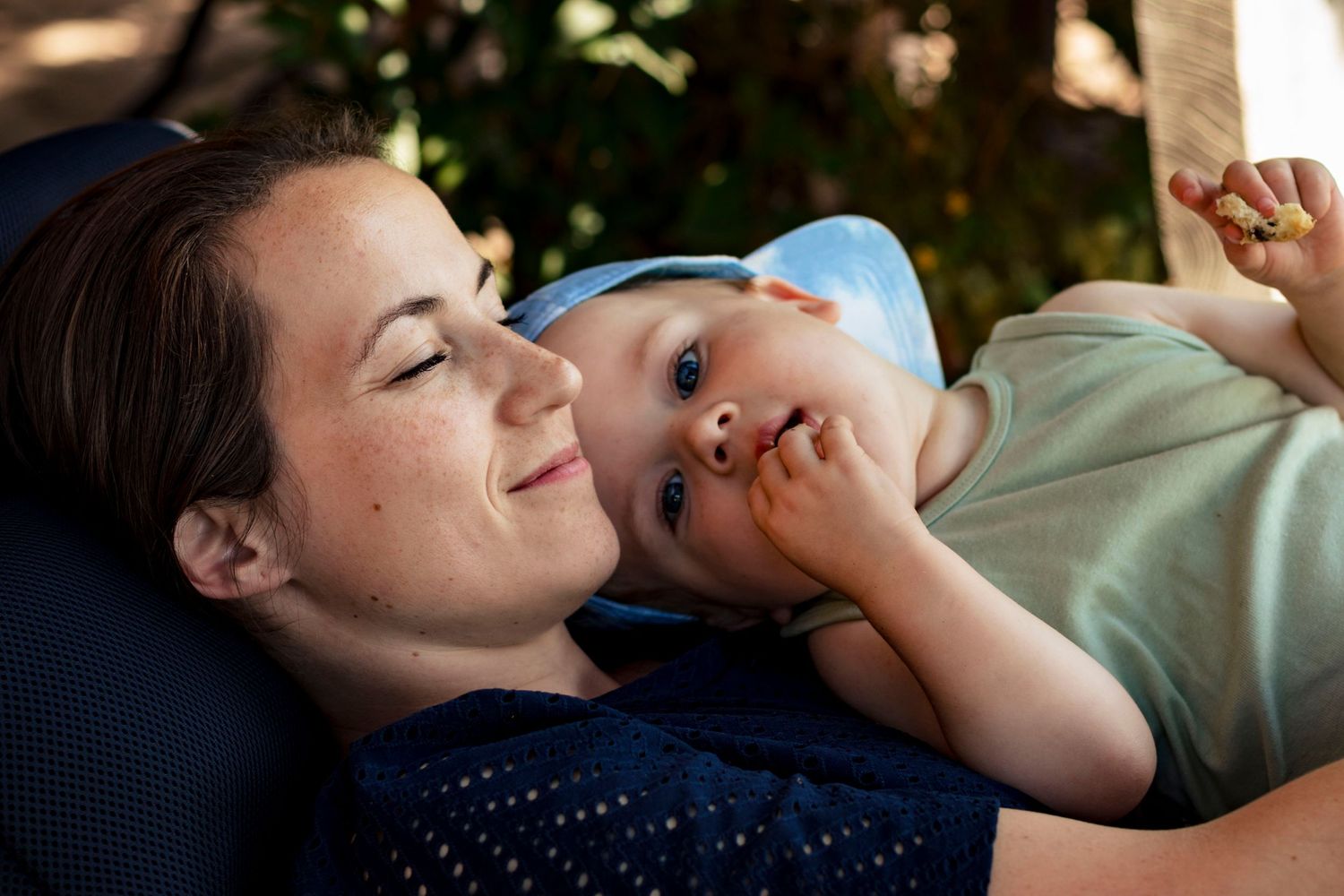 Tender moment of relaxation shared outdoors on a sunny afternoon.