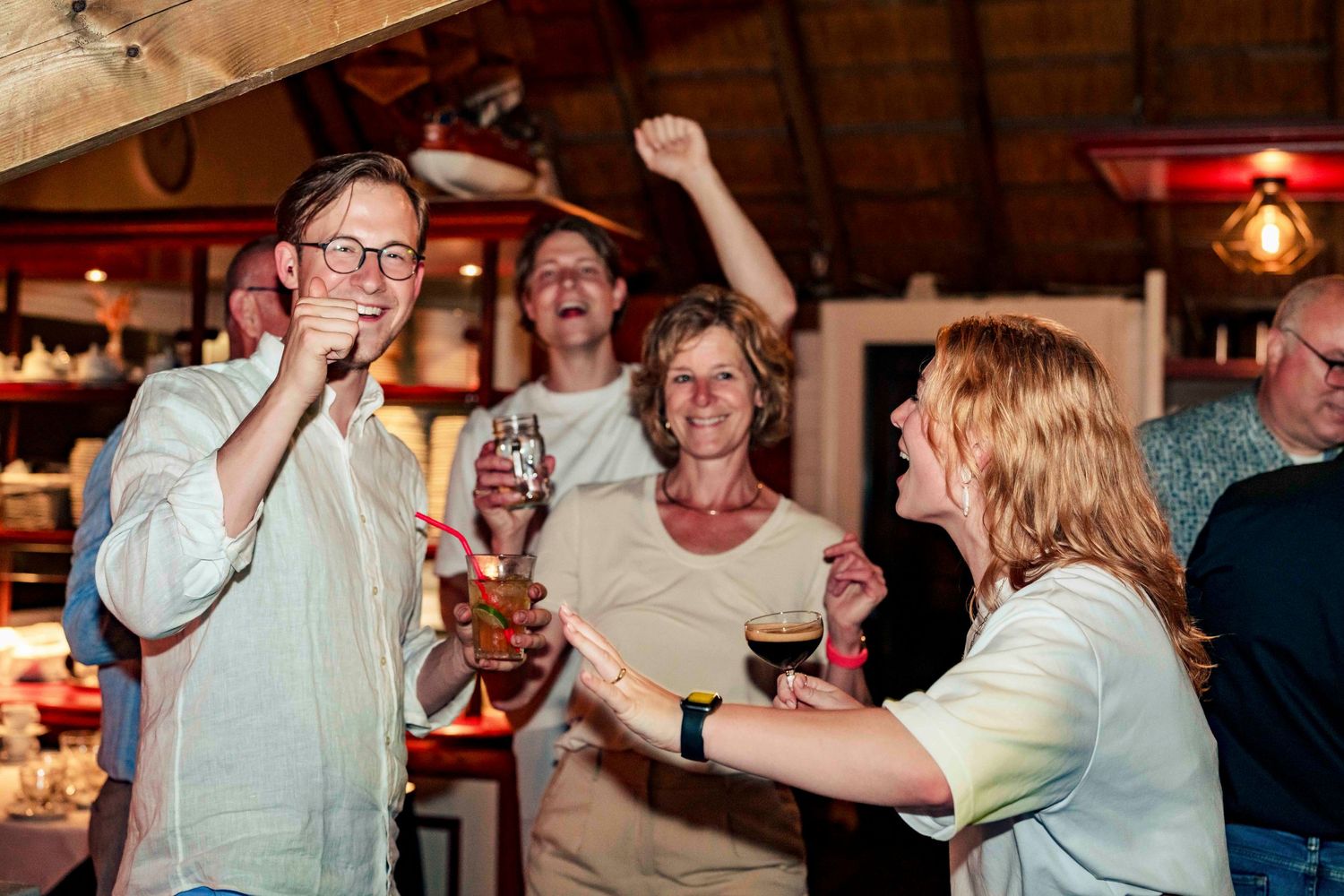 People celebrating and dancing at a lively party in a rustic indoor venue.