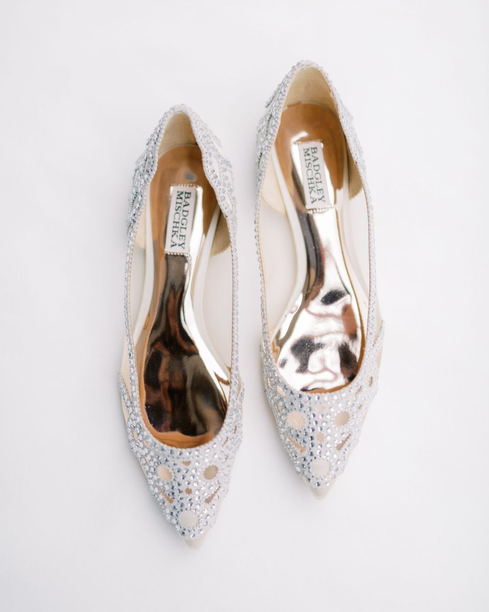 Glittery silver bridal flats with ornate detailing photographed from above.