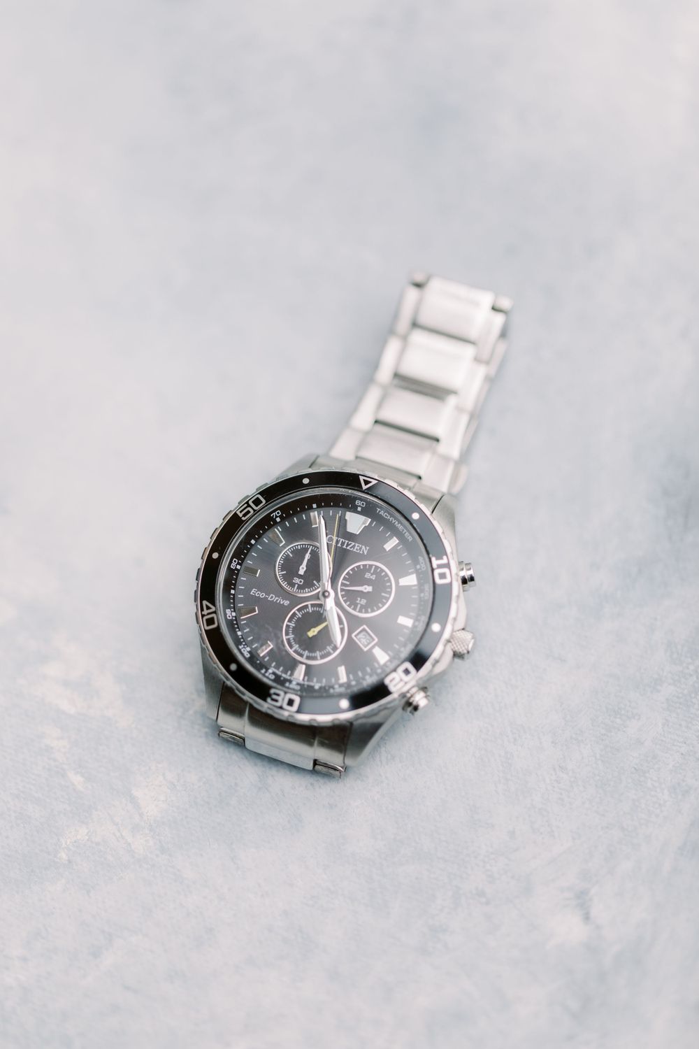 Stainless steel chronograph watch with black face on light gray surface.